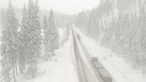 Descending aerial shot of trucks driving through snowy conditions