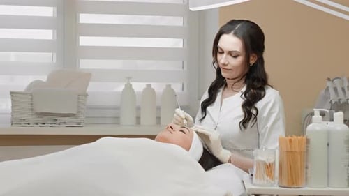 Woman Receives Eyebrow Treatment in Bright Medical Room