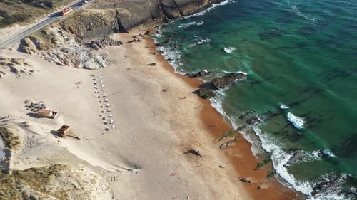 Luftaufnahme des Sandstrandes mit Wellen, die gegen Felsen prallen