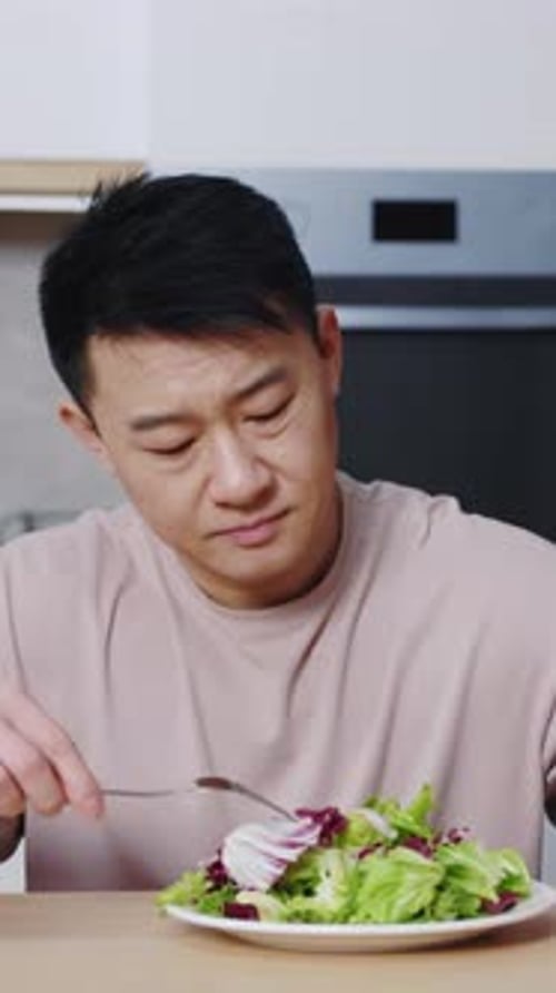 Close Up Asian Man Sitting at Table Looking Sad and Bored with Diet Don't Want to Eat Salad At the
