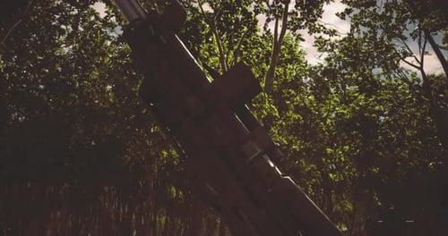 Gun Positioned Among Dense Greenery During a Bright Daylight Setting