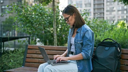 Woman Typing on Laptop in Urban Park