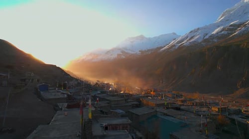 Aerial Fly Over Manang Village House Rooftops with Stunning Sunrise Over Valley and Snowy Peaks in