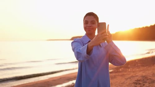 Smiling Woman Takes Photos on Beach at Sunset