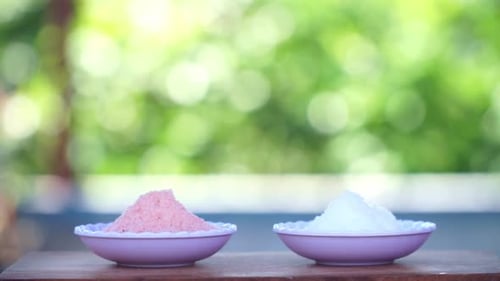 a small bowl of himalayan salt and sea salt with blur nature background. Pink salt and white salt.