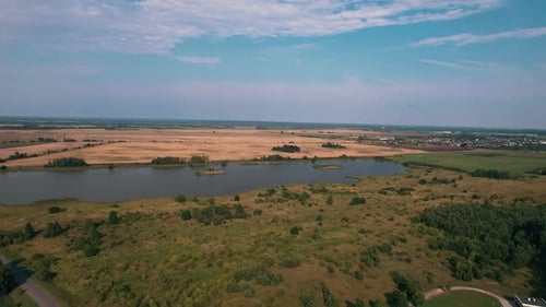Aerial View of Pond with Islands Surrounded By Fields and Village with Farmsteads in Valley Panorama