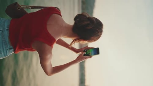 Close-up, girl stand on the embankment and takes pictures of sunrise on mobile phone