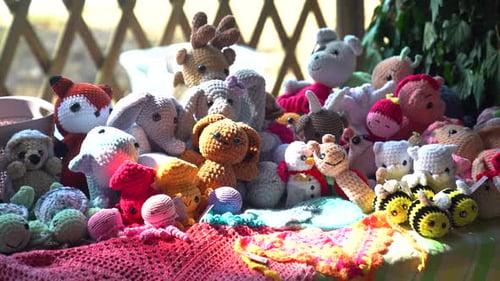 Handgemachtes gehäkeltes Tierspielzeug und Puppen, ausgestellt auf einem Handwerkstisch im Sonnenlicht