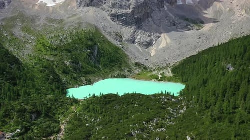 Lake Sorapis bright turqoise water in the Dolomites Italy, forward aerial