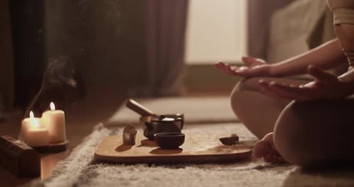 Female Meditating Near Tea and Incense