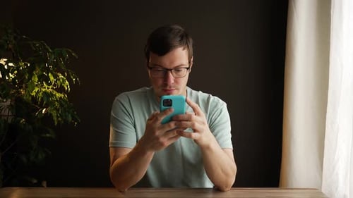 Young Adult Reacts to Phone Content, Smiling