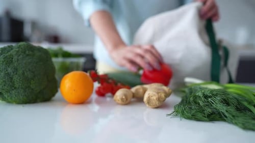En una cocina contemporánea, una mujer descarga alimentos frescos con bolsas ecológicas