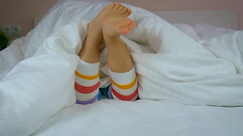 Child's Legs and Feet Stick Out of Bed