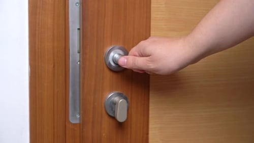 Hand Opens Wooden Door with Silver Handle