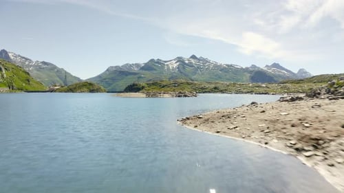 Flight forward low over mountain lake towards island in the middle. Slow climb in front of the islan