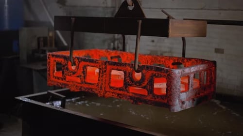 Transporting Glowing Metal Casting in Foundry