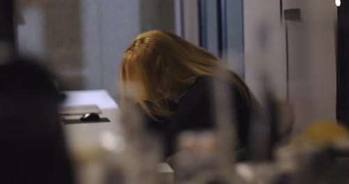 Frustrated businesswoman sits at conference table with hands clasped in front of face,