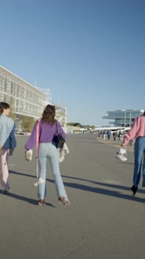 Three Girls Roller Skate on Road By Water While Holding Their Shoes