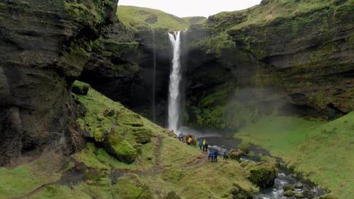 Hikers View Massive Waterfall Plunging into Lush Green Canyon Below