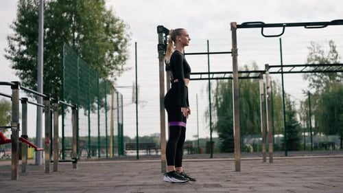 Woman Doing Squats with Resistance Band Outdoors