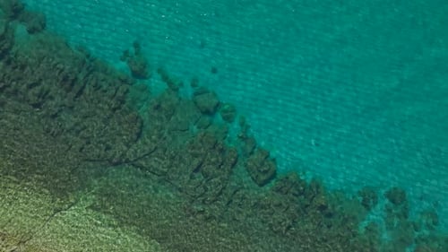 Aerial Video Aerial Perspective of a Rocky Shoreline with Clear Blue Waters and Gentle Ocean Waves