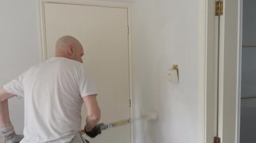 Maler und Dekorateur, der frische Farbe in einem Wohninterieur aufträgt.