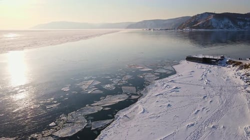 A Snowy Shoreline Next to a Frozen Lake Seen From an Aerial View