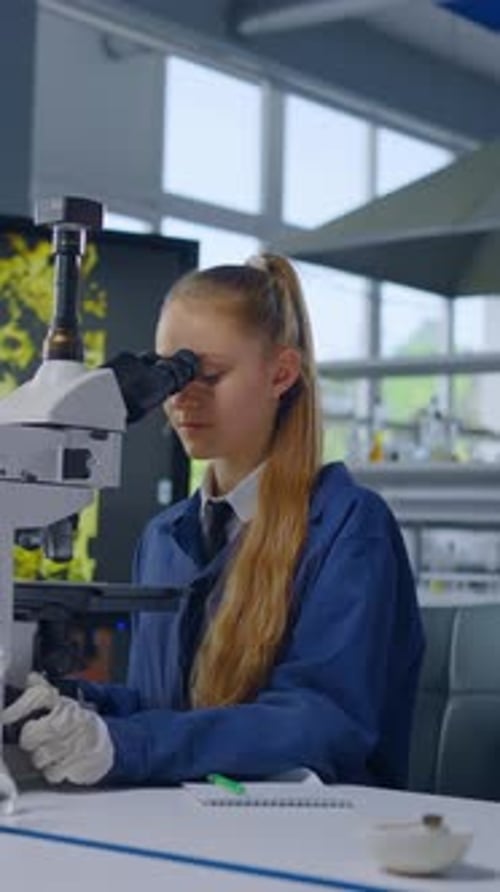 Teenage Girl Using Microscope in Lab with Mentor