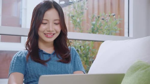 Young asian business woman working with laptop sitting on sofa in home office.
