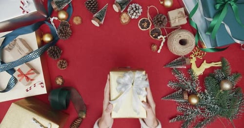 Top view of girl hands unpacking present gift box winter christmas decorations on red background.