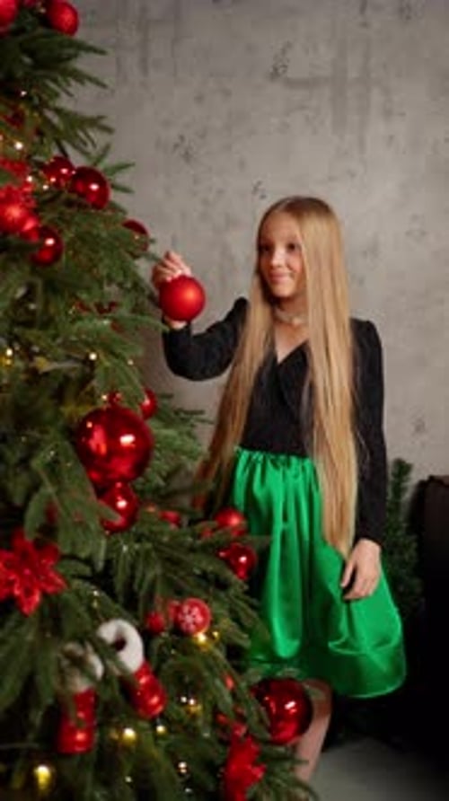 Teenage Girl Decorates Christmas Tree with Red Decorations Concept of Preparing for New Year