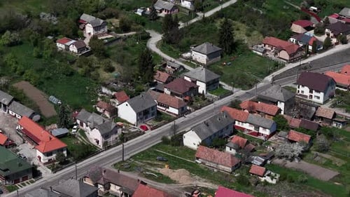 Una vista aérea revela un pintoresco pueblo rural enclavado entre verdes colinas, con carreteras sinuosas y