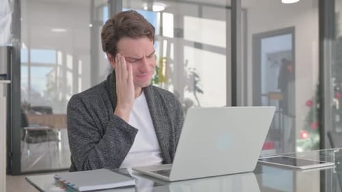 Frustrated Man Working on Laptop in Office