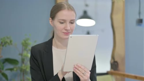 Woman Uses Tablet Device in Modern Workplace Setting