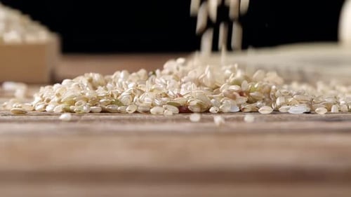 Rice Being Poured onto a Wooden Table