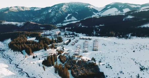 Long Panoramic Aerial Shot of Idyllic Winter Ski Resort Village Buildings in Sunny Morning Snowy