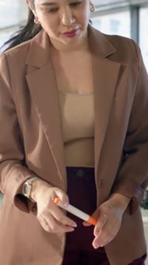 Vertical video: After reviewing graphs woman in blazer picking up marker at desk annotating data