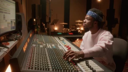 Sound Engineer Operating Studio Mixing Board and Looking at Computer Screen