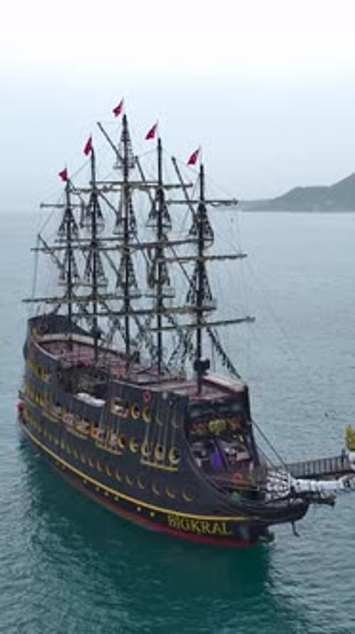 Vertikales Video: Von Touristen gefülltes Piratenschiff, das unter dem klaren blauen Himmel segelt
