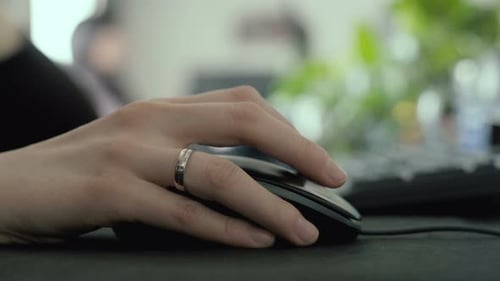 Hand using a mouse on a desk in an office, selective focus scrolling and clicking