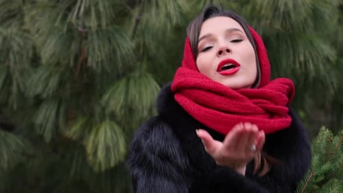 Smiling Woman with Christmas Tree Blowing Kiss