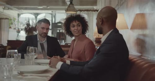 Three Businesspeople having a Meeting in a Restaurant using Laptop