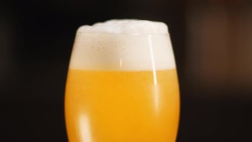 Close up of craft Beer being poured in to a goblet beer glass, dark background