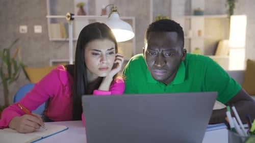 Young african man and caucasian woman working with laptop.