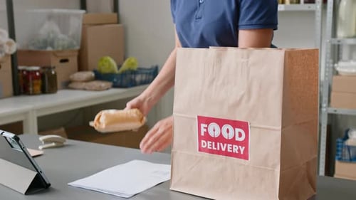 Female Associate Packing Groceries while Fulfilling Order at Dark Supermarket