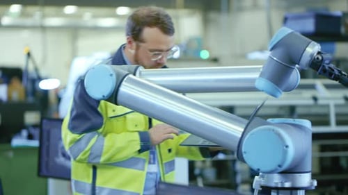 À l'usine : un ingénieur en automatisation utilise un ordinateur portable pour programmer un bras robotique. Une nouvelle ère pour Automatic M