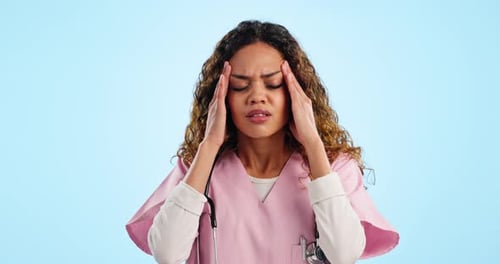 Headache, nurse and pain of woman in studio with burnout, stress and medical mistake on blue
