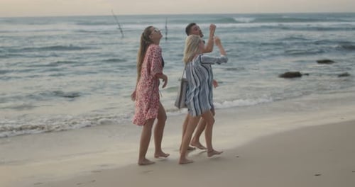 Two Beautiful Women and Handsome Fit Man Walking Along the Beach, Talking and Having Fun. Gorgeous