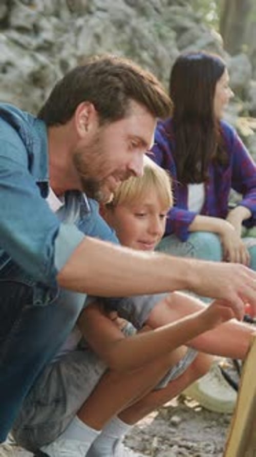 Father and Son Making Together Campfire Enjoy Spend Camping Evening Time Outdoors on Nature Smiling