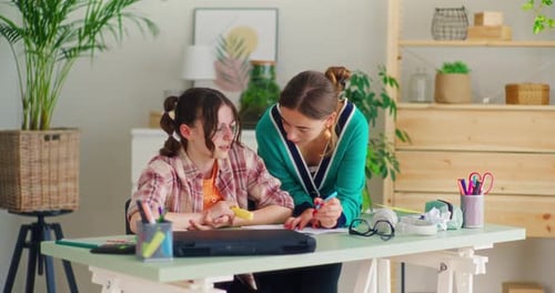 Young Woman Helping Teen Girl With Homework Indoors